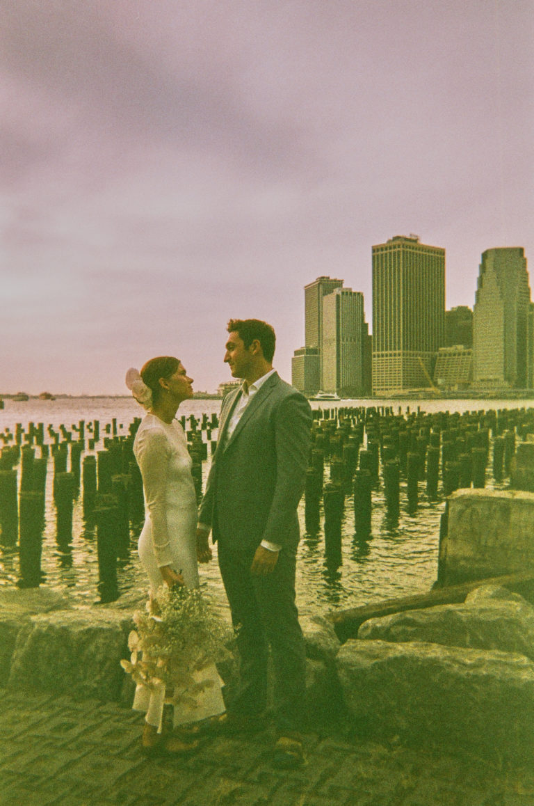 Wedding Photography in New York, couple holding hands and looking at each other with cityscape in the background and a stylized edit
